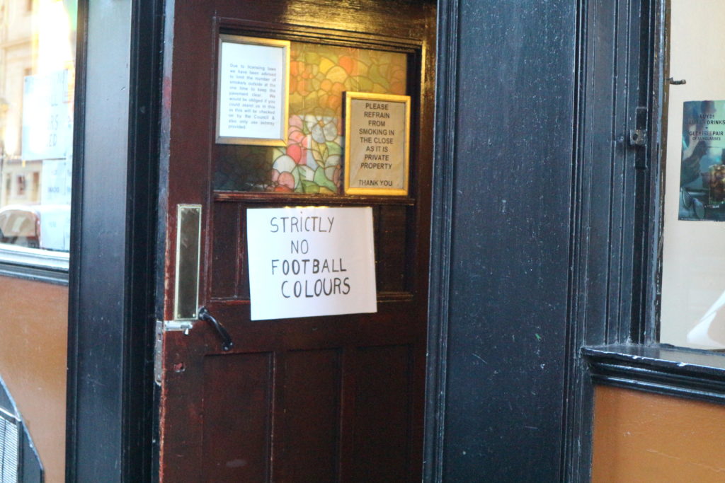 "No Football Colors Allowed" reads a sign outside of a bar in Scotland.